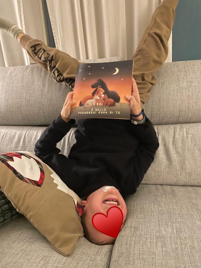 Un bambino felice sul divano che legge il libretto a Radici scritto su misura per lui